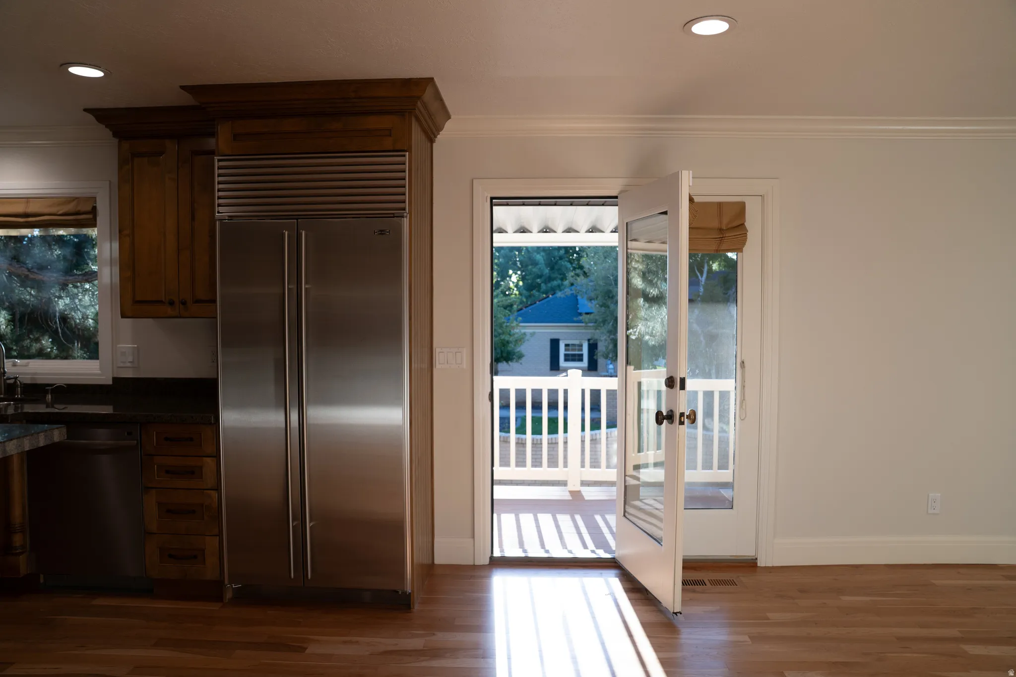Hardwood flooring, recessed lighting, stainless steel refrigerator, wood cabinetry, and French doors opening to a deck