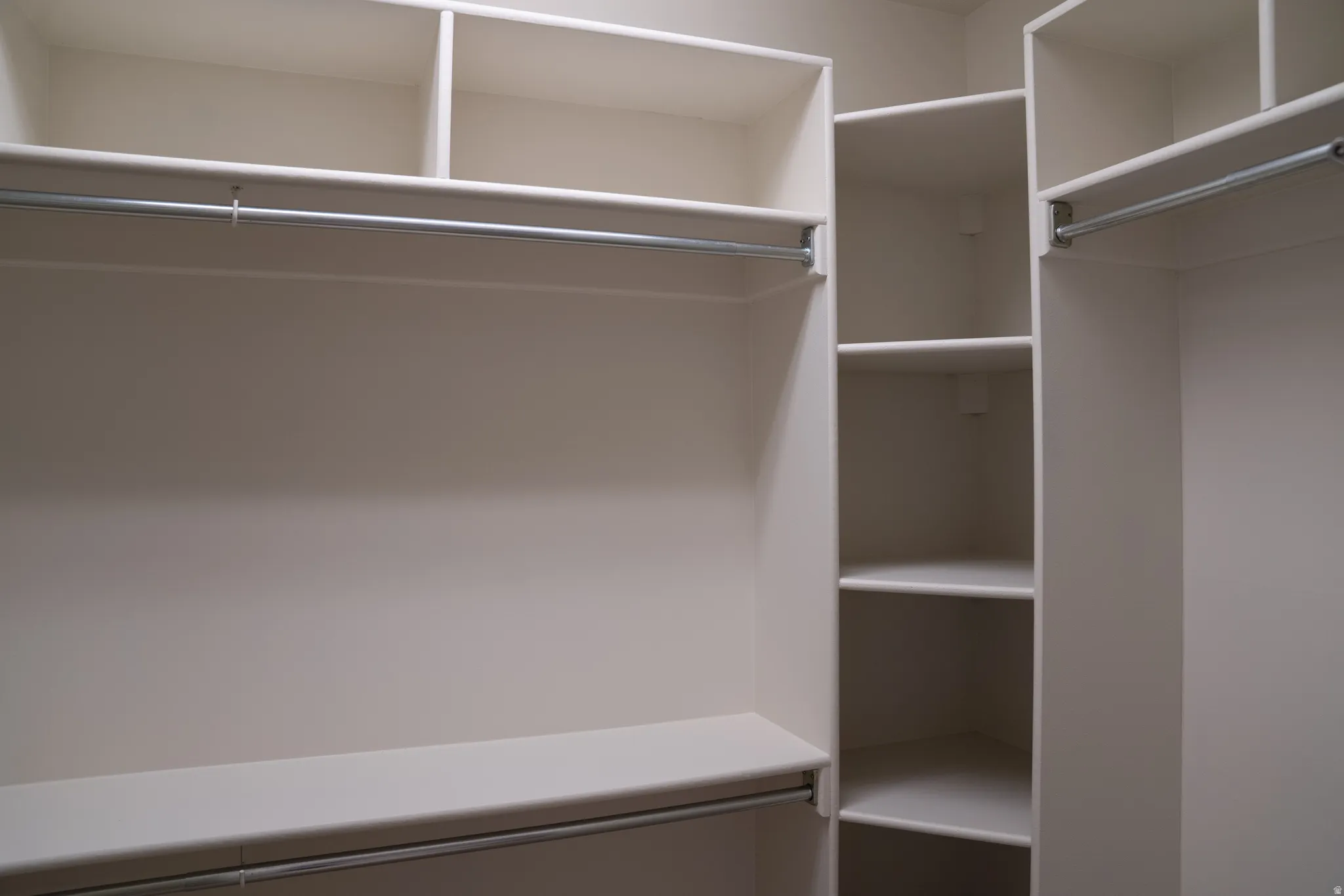 Custom closet system with multiple shelving units and integrated hanging rods
