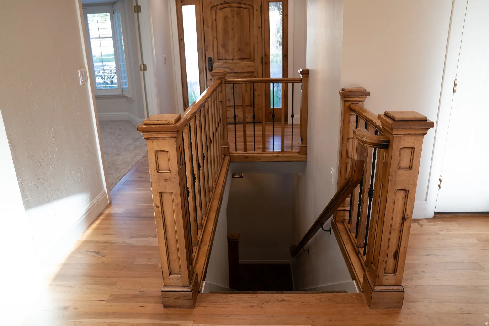 Wood-finish flooring, staircase with wood newel posts, wood handrail, and wrought iron balusters