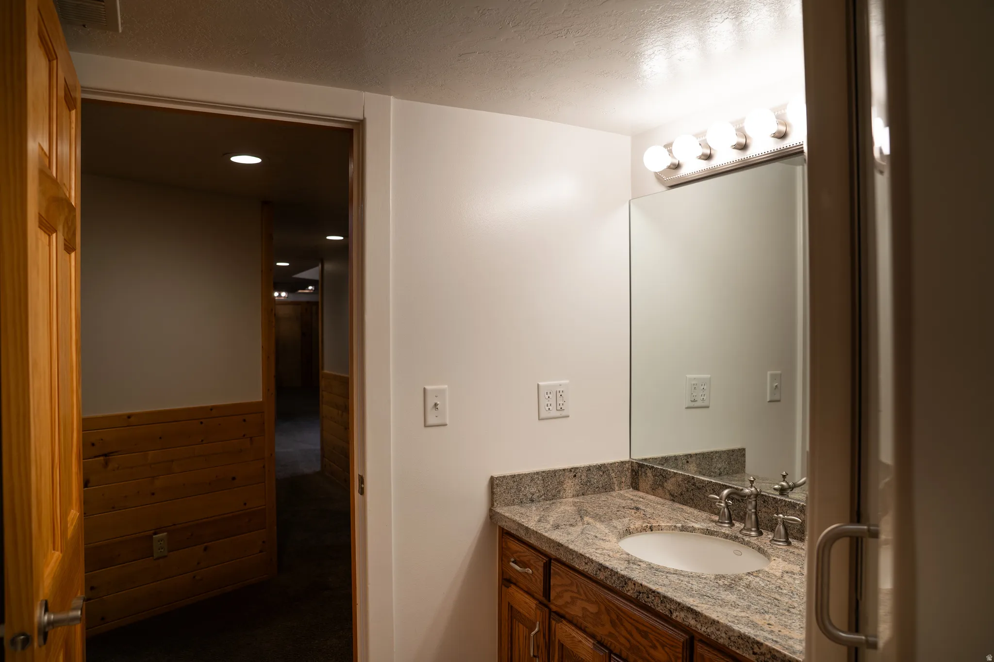Vanity with a polished stone countertop, undermount sink, and brushed nickel fixtures