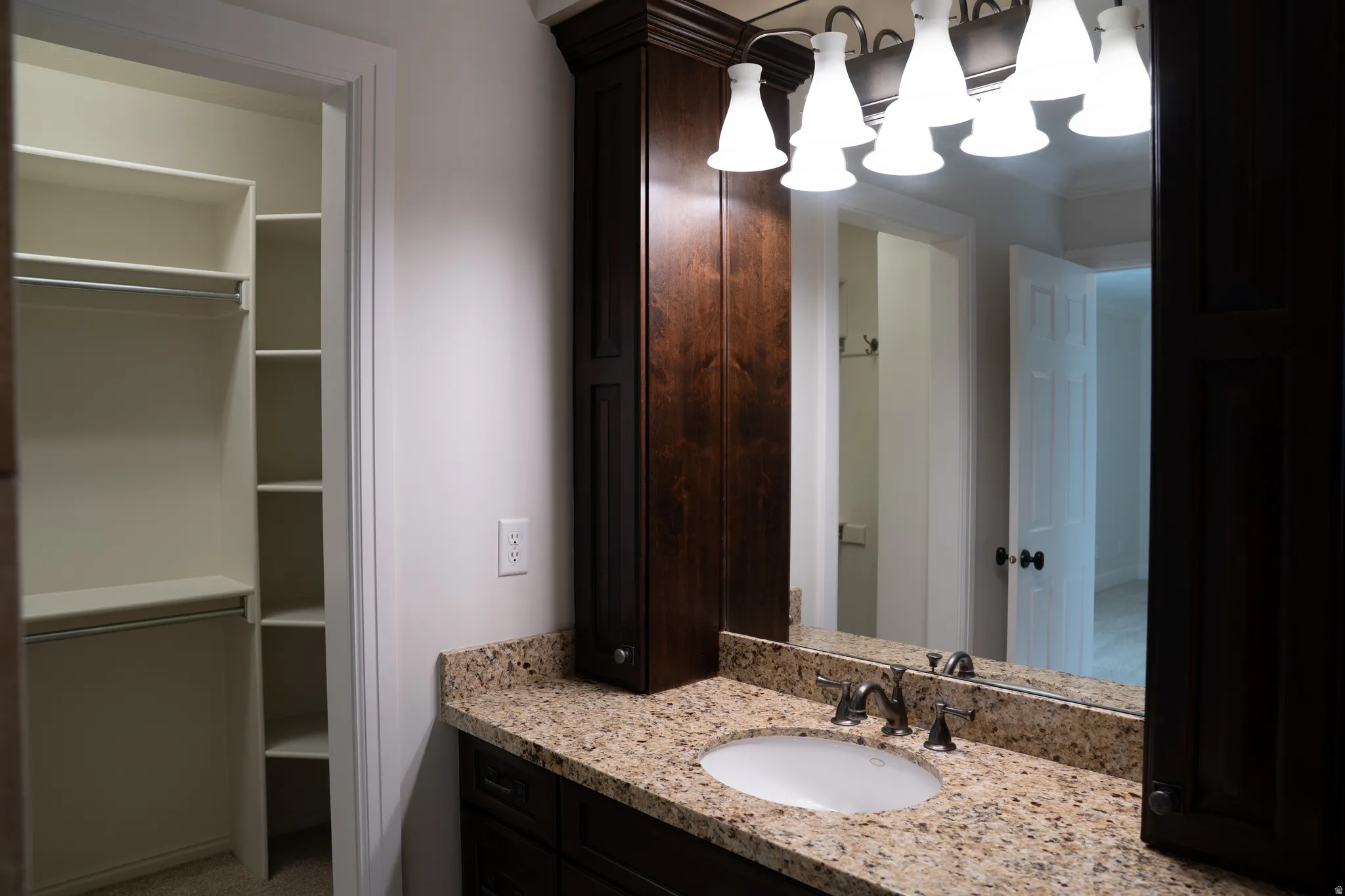 Vanity with light-toned countertop, integrated sink, and dark wood-finish cabinetry