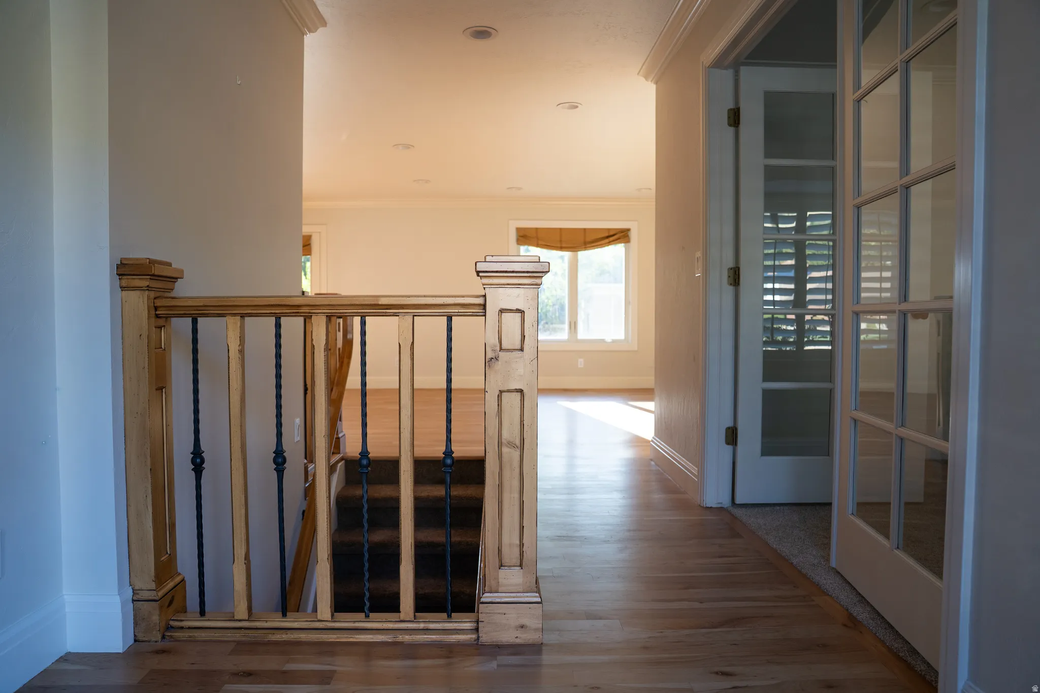 Hardwood flooring, French doors, staircase with wood banister and wrought iron spindles, recessed lighting, and crown molding