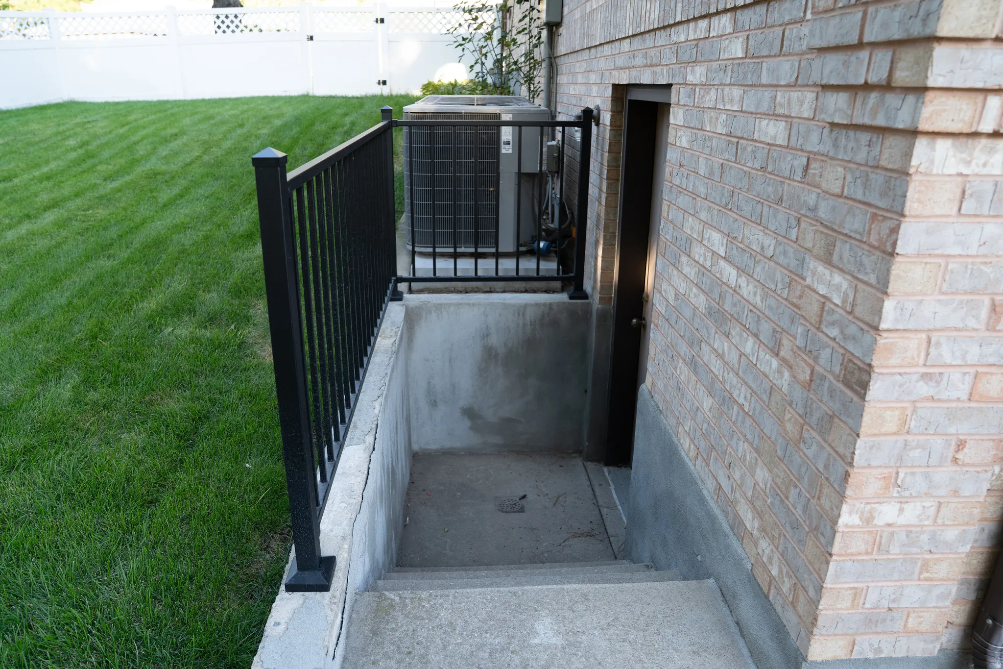 Brick exterior featuring a basement entry with concrete steps and black metal railing
