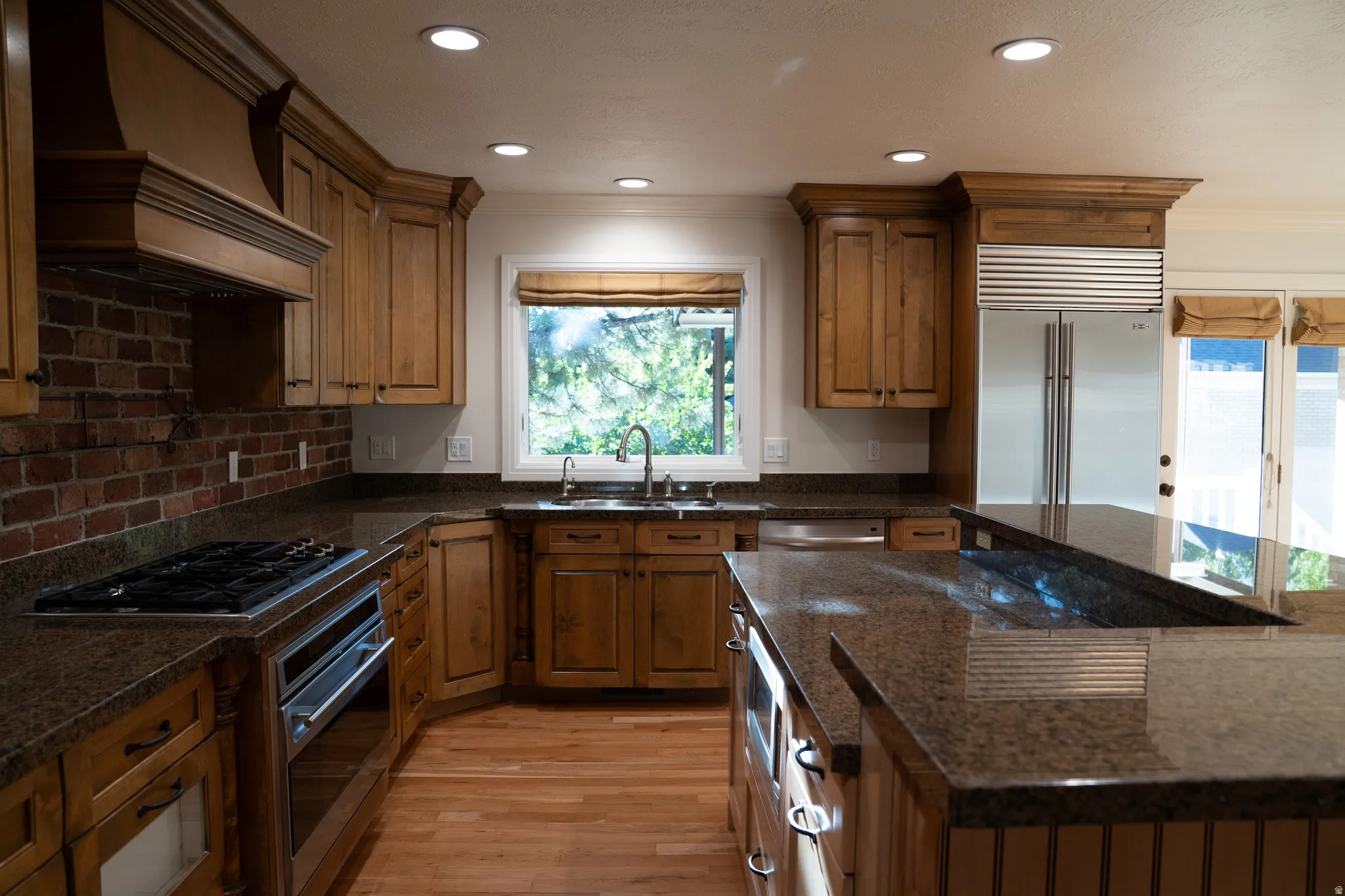 Wood cabinetry with crown molding, stainless steel appliances, brick backsplash, wood-finish flooring, and recessed lighting