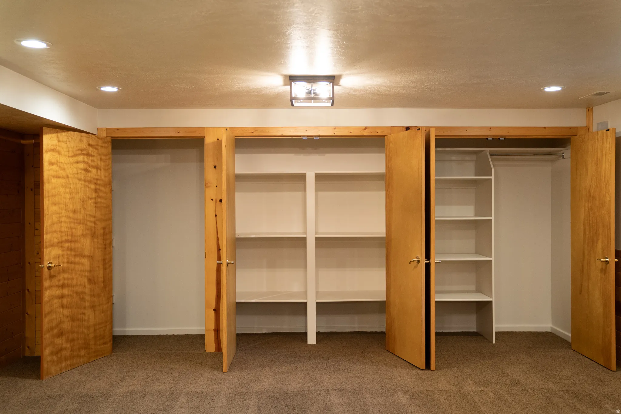 Recessed ceiling lighting, flush mount ceiling light fixture, wood-finish bi-fold closet doors, built-in closet shelving, and built-in closet hanging rods