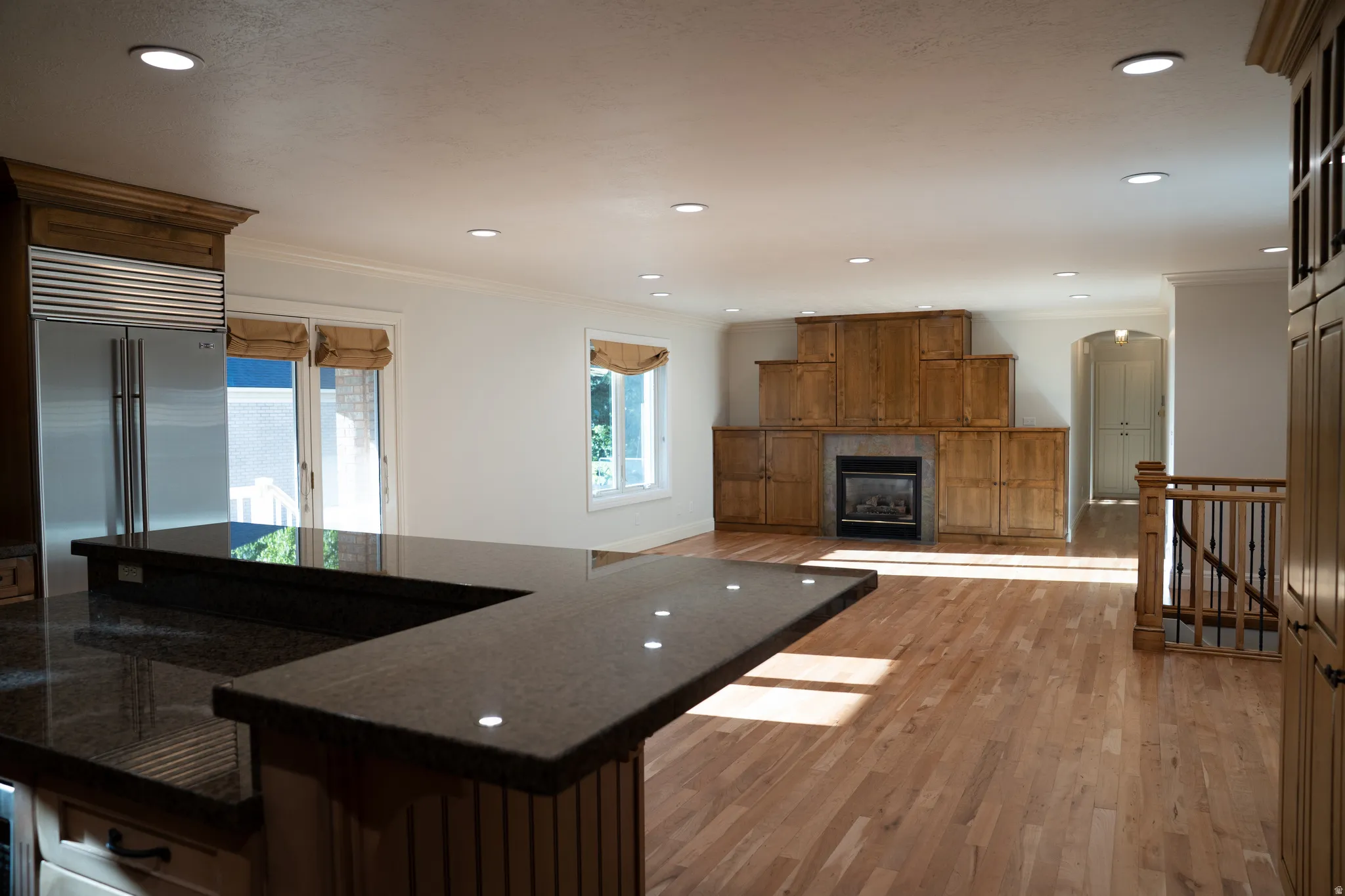 Stainless steel refrigerator, granite countertops, hardwood flooring, built-in cabinetry, and a fireplace