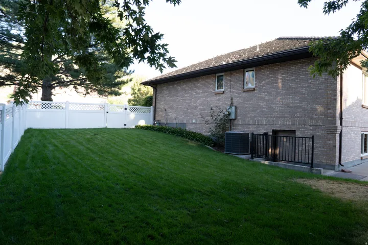 Expansive lawn with a white lattice-top fence and gate