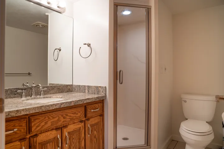 Vanity with granite-style countertop, wood-finish cabinetry, and an undermount sink