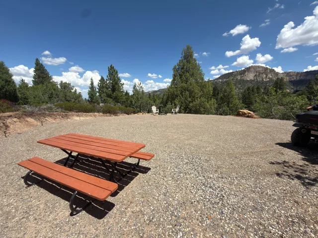 Expansive gravel area with perimeter tree line and distant mountain formation