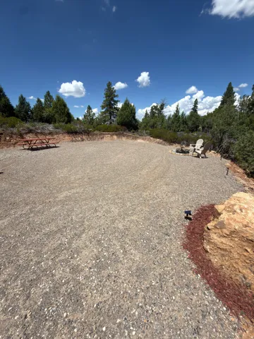 Gravel-surfaced outdoor area with a picnic table, fire pit, and integrated ground lighting
