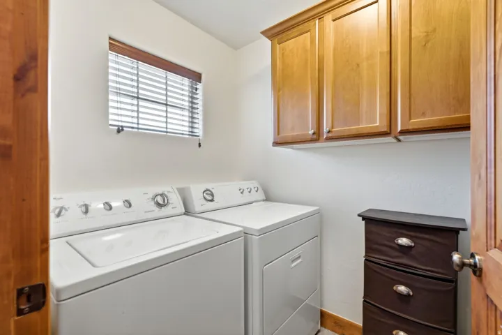 Laundry area featuring built-in wood cabinetry, a window with horizontal blinds, and a wood-finish door frame