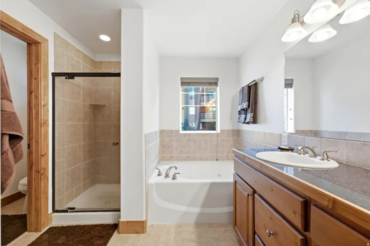 Bathroom featuring a tiled shower enclosure with a glass door, a built-in bathtub, a vanity with a drop-in sink, and a framed mirror