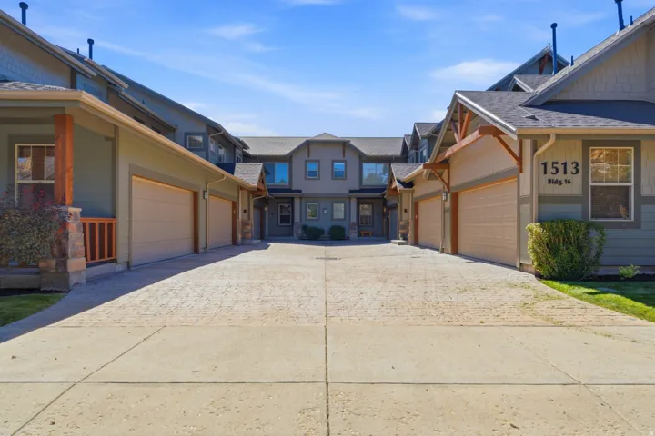 Paved driveway with concrete borders, leading to residences featuring attached garages with beige doors