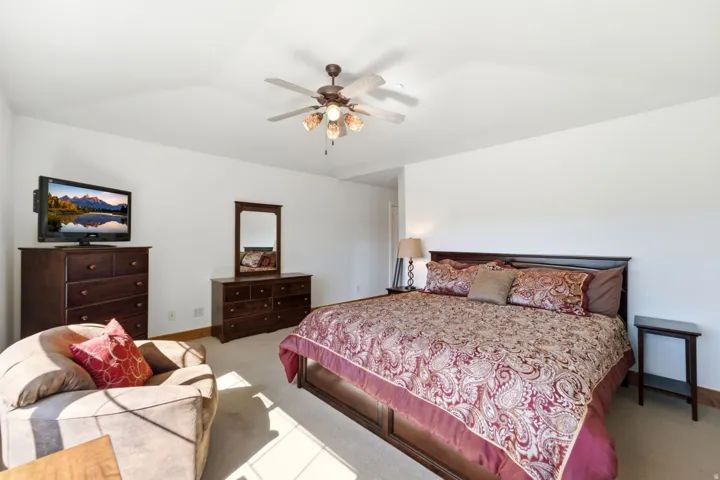 Vaulted ceiling with a ceiling fan, light-colored carpet, and white walls