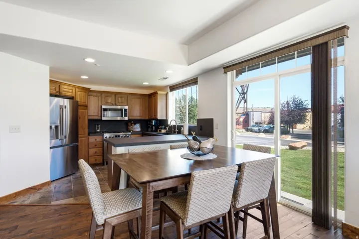 Recessed lighting, wood-finish flooring, stainless steel appliances, sliding glass door, and a kitchen island with seating