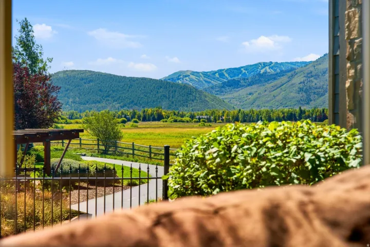 Expansive outdoor setting featuring a paved pathway, decorative metal fencing, and a wooden pergola structure