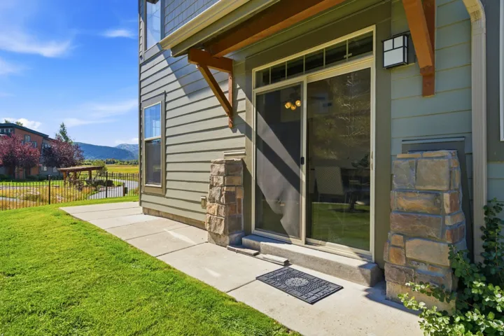 Sliding glass door entry, stone veneer architectural elements, and wood-finish accent beams