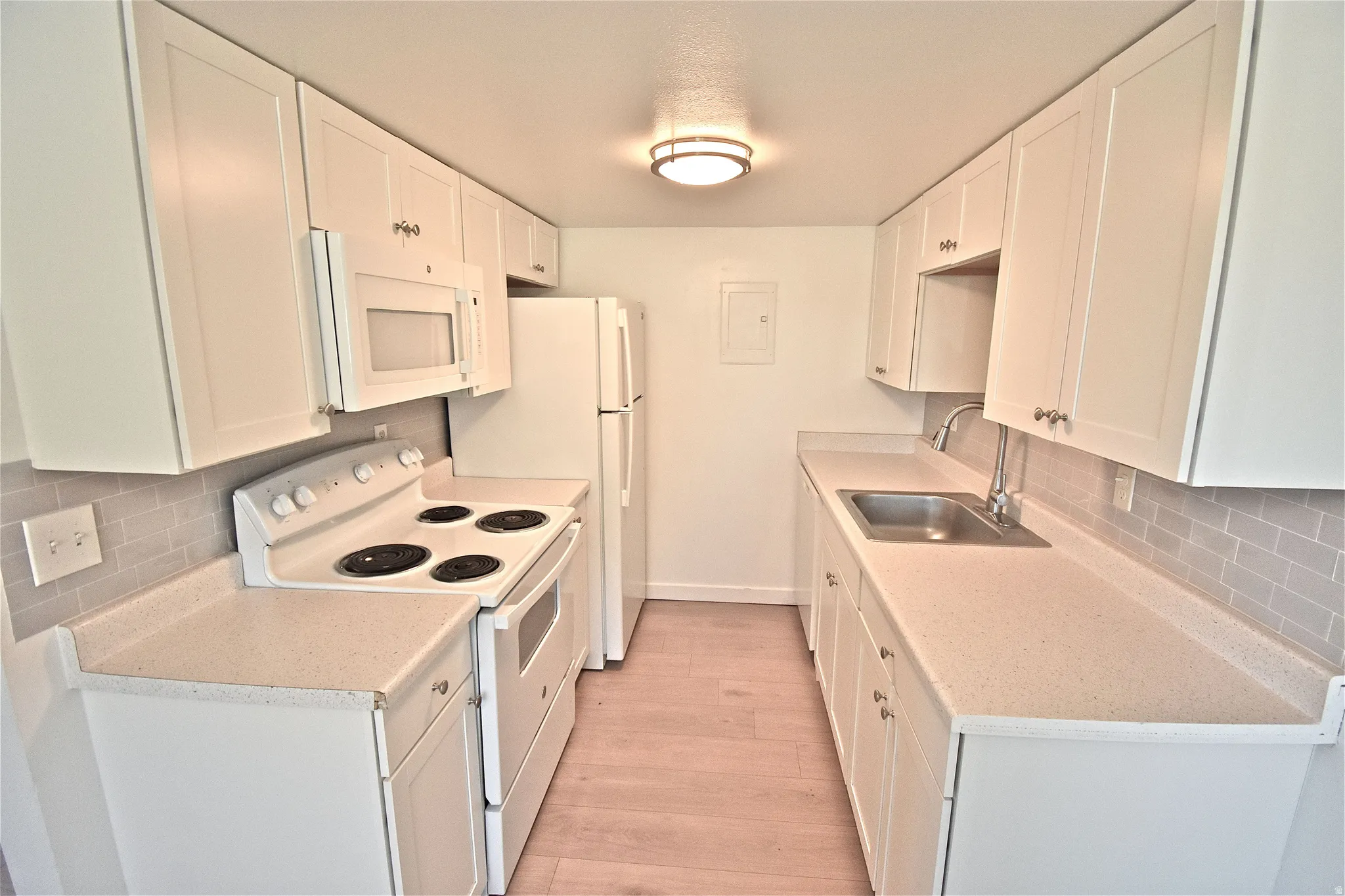 Kitchen with new cabinets, counters, tile backsplash, range, microwave and refrigerator (2022)