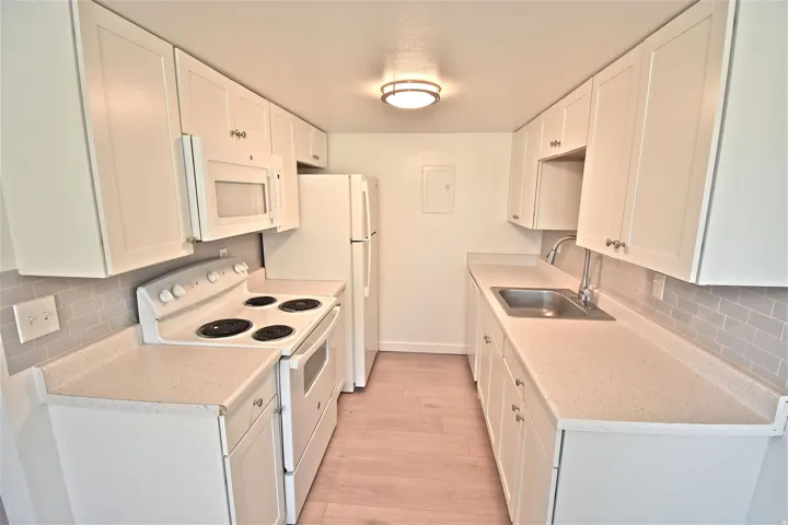 Kitchen with new cabinets, counters, tile backsplash, range, microwave and refrigerator (2022)
