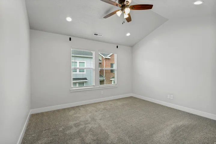 Vaulted ceiling with recessed lighting, ceiling fan, and carpeted flooring