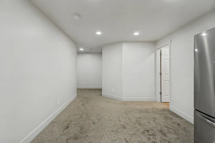 Recessed ceiling lighting illuminates the carpeted floor and white painted walls