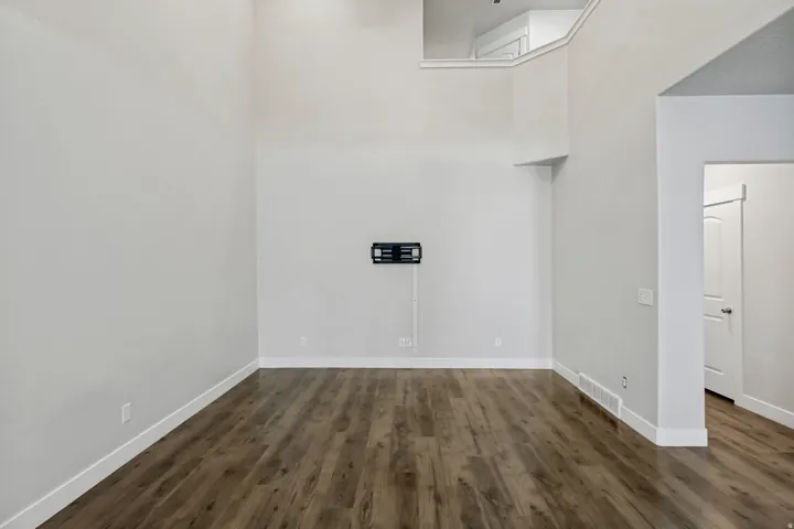 Spacious room with high ceilings, wood-finish flooring, and a wall-mounted bracket