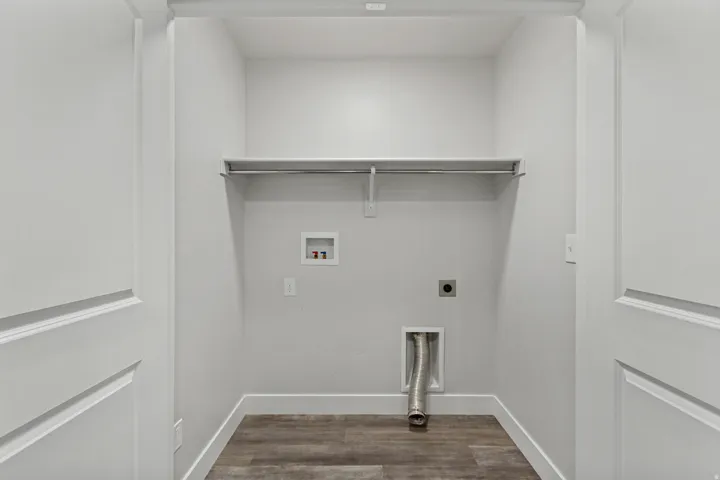 Dedicated laundry area with wood-finish flooring, light gray wall paint, and a built-in wire shelf