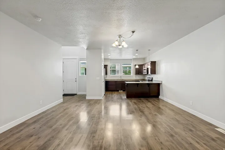 Open concept living area featuring wood-finish flooring, recessed lighting, and a white entry door
