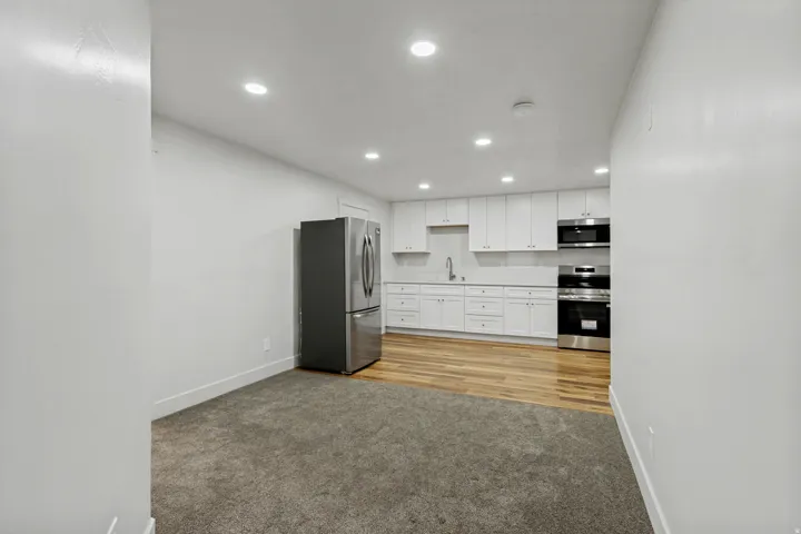 Kitchen featuring white cabinetry, stainless steel appliances, recessed lighting, and wood-finish flooring