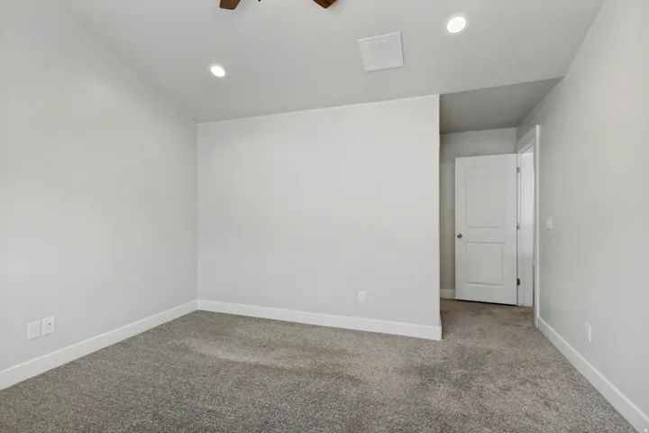 Plush grey carpeting, recessed lighting, and a neutral wall palette