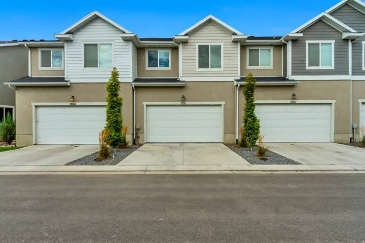 Contemporary exterior featuring stucco and horizontal siding, individual garage doors, and concrete driveways with decorative rock accents