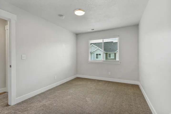 Recessed lighting, neutral wall paint, window with horizontal blinds, gray carpet flooring, and white trim throughout