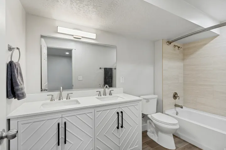 Double vanity with white countertops, dual undermount sinks, and decorative paneling on cabinetry