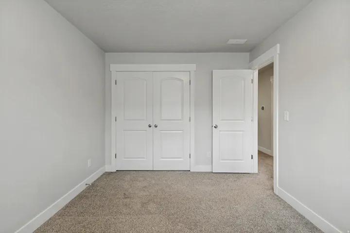 Neutral wall tones, carpet flooring, a two-panel interior door, and a two-panel bifold closet door