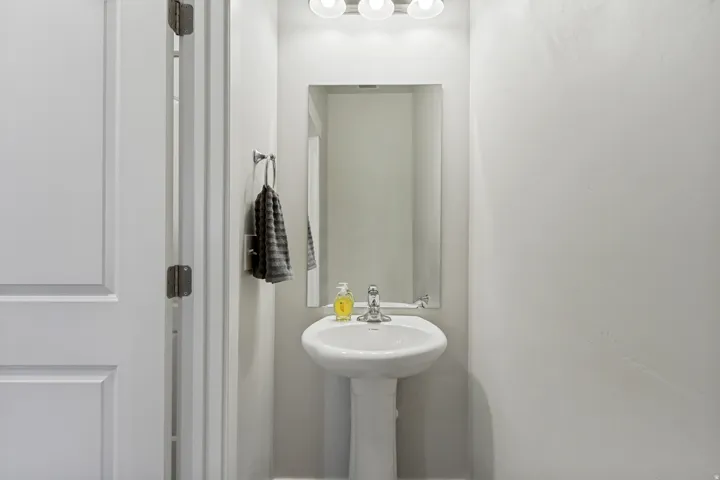 Pedestal sink with chrome faucet, framed mirror, and integrated vanity lighting