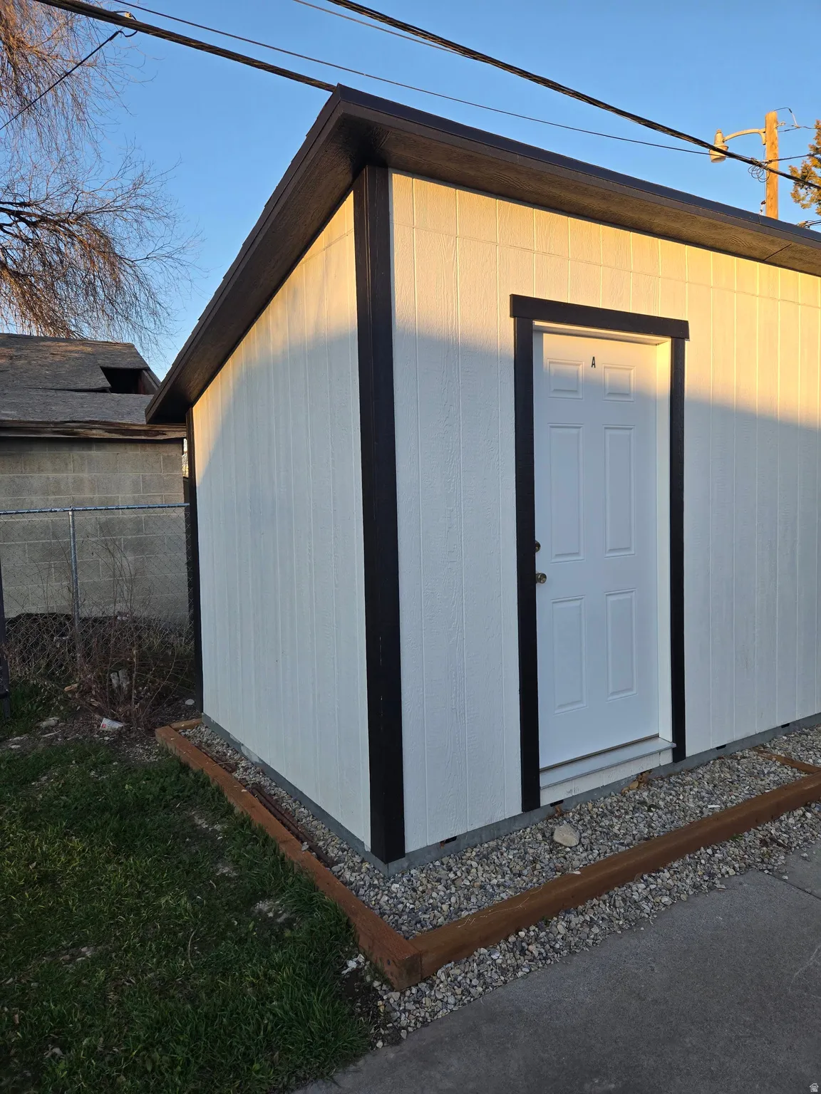 Exterior storage structure with white panel siding and dark trim