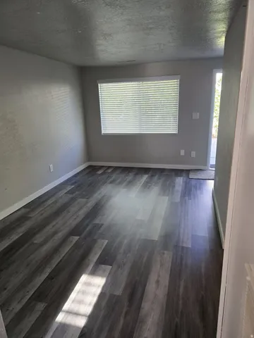 Gray wood-finish flooring with white baseboards and neutral wall tones