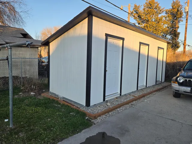 Detached storage building with multiple entry doors and a sloped roof