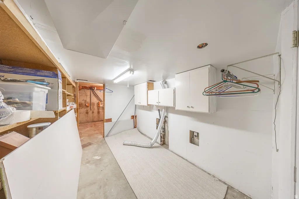 Utility space featuring built-in shelving, wall-mounted cabinetry, and a concrete floor