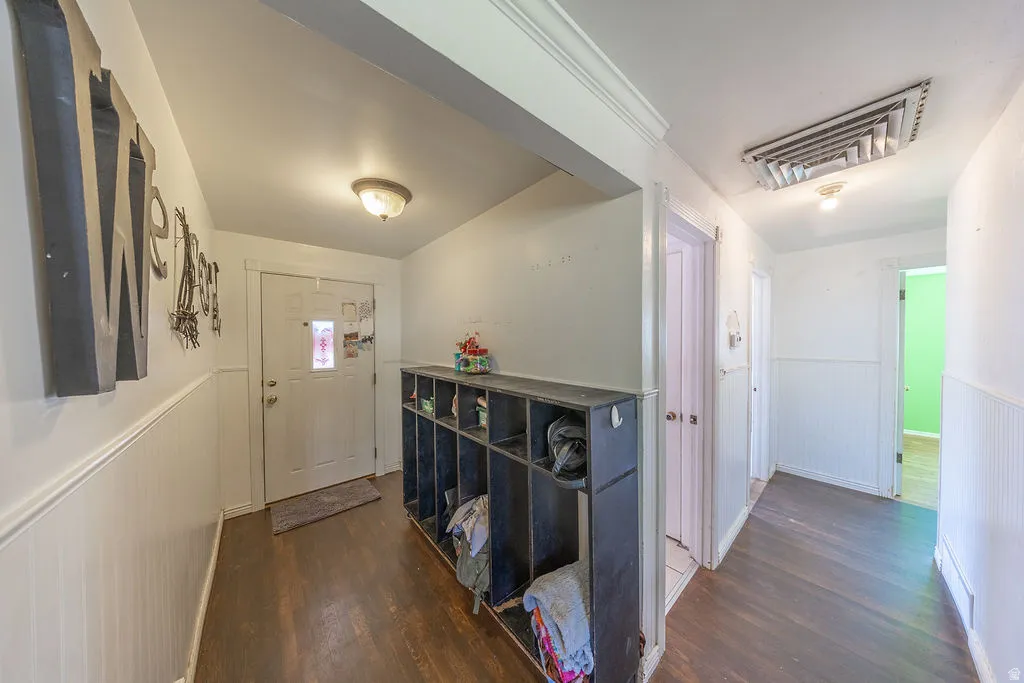 Entryway featuring wood-finish flooring, white wainscoting, and a built-in storage cubby