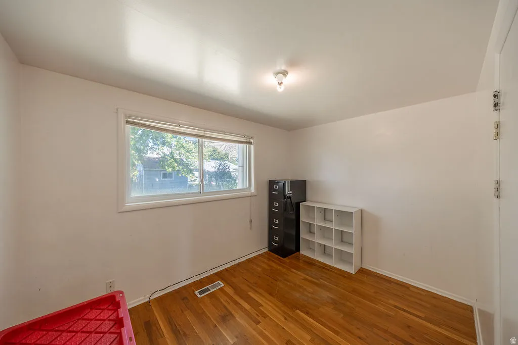 Wood-finish flooring with white walls and a large window