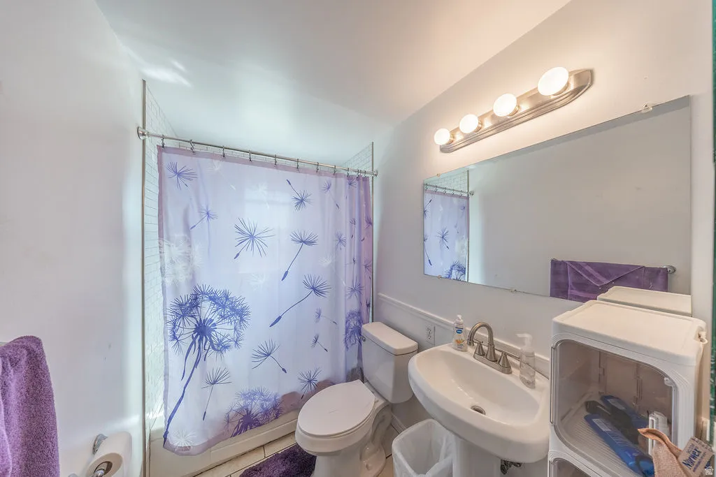 Pedestal sink with a single-handle faucet, wall-mounted mirror, and overhead vanity lighting