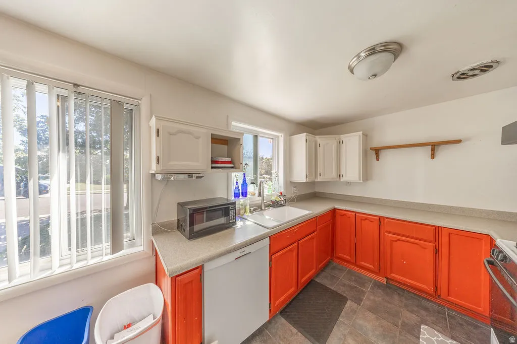Kitchen featuring white upper cabinetry, orange lower cabinetry, a white built-in dishwasher, and a dual-basin sink