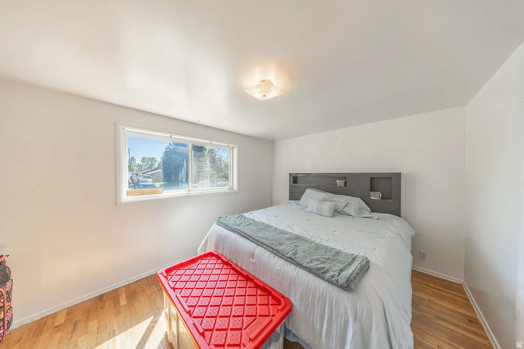 Wood-finish flooring, white walls, built-in headboard shelving, and a flush mount ceiling light