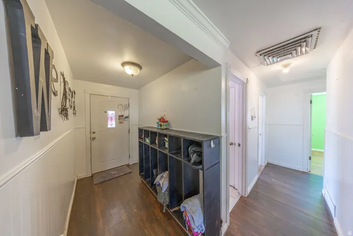 Entryway featuring wood-finish flooring, white wainscoting, and a built-in storage cubby