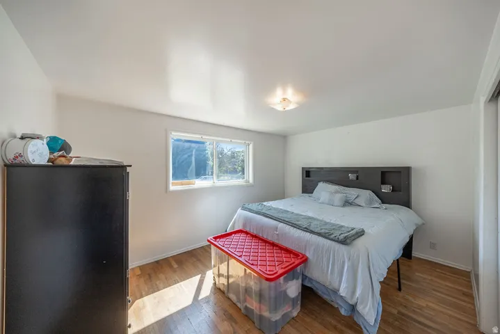 Hardwood flooring, white painted walls, window with natural light, flush mount ceiling light fixture, and a built-in closet with sliding doors