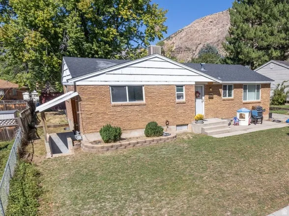 Brick exterior residence with a front lawn and established trees
