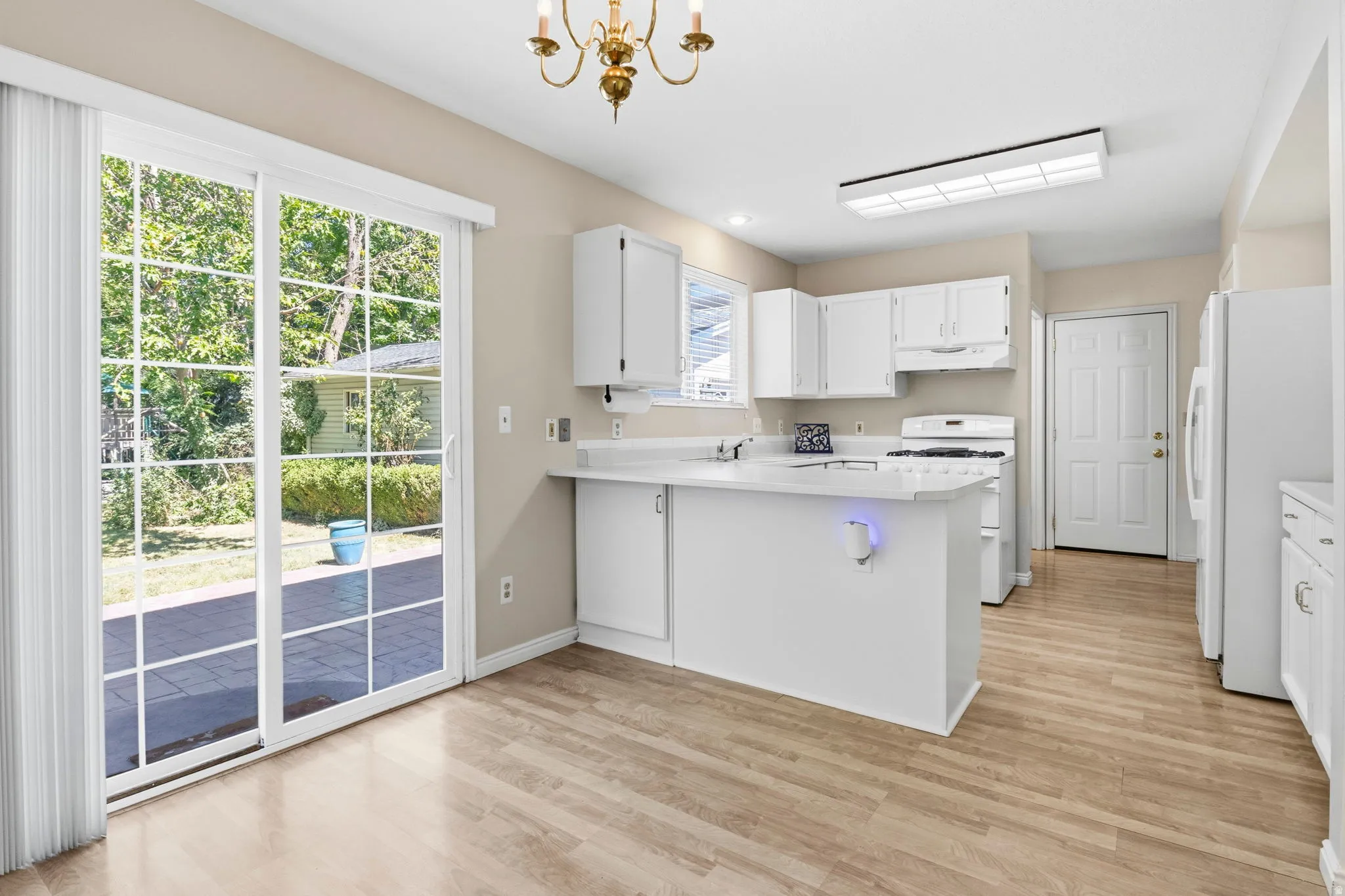 Kitchen with wood-finish flooring, white cabinetry, and white appliances