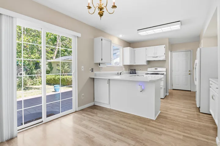 Kitchen with wood-finish flooring, white cabinetry, and white appliances