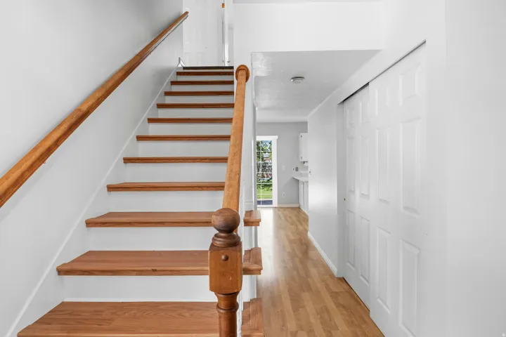 Staircase with wood treads and handrail, featuring white risers and walls